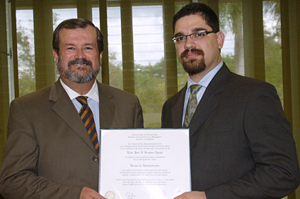 El rector del RUM, doctor Jorge Iván Vélez Arocho (izquierda) entrega al licenciado José A. Frontera Agenjo el pergamino que oficializa su designación como Decano de Administración.