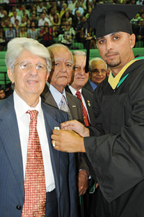 Guillermo Irizarry, egresado del Colegio hace 70 años, recibe el broche oficial de manos del estudiante Félix R. Rollet.