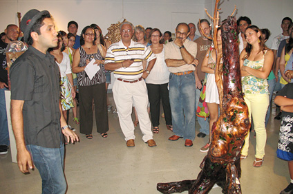 El joven Saúl Cubero Patiño muestra su pieza La Andalucía hiperpluvia compuesta de un tronco de madera y vídrios.