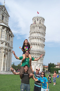 Algunos de los participantes del viaje estudiantil forman una torre humana frente a la Torre inclinada de Pisa.