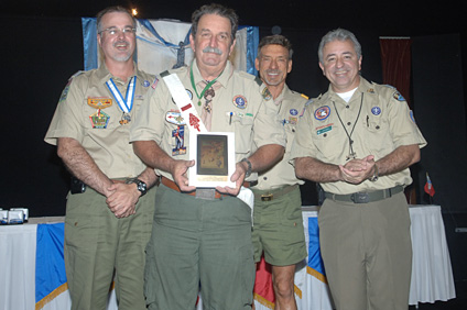 Carlos Díaz sostiene el Premio Centenario de Servicio que le entregaron el doctor Luis Montalvo, comisionado del Concilio; Bob Denlinger, scout executive; y Juan Salgado, presidente del Concilio de los Niños Escuchas de Puerto Rico.