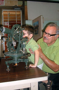 El profesor Julio C. Ríos mientras le mostraba los instrumentos de agrimensura a su nieto menor, Alex. Foto suministrada