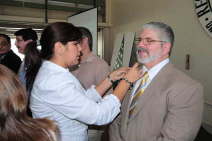 La licenciada Lisbeth Rivera le coloca el lazo dorado al profesor Aristides Armstrong, decano interino de Ciencias Agrícolas.