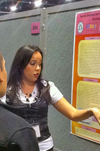 Rosa M. Santana le explica a otro estudiante los conceptos que presentó en su póster científico.