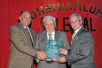 El ingeniero Radamés Balzac, presidente de la Fundación y Asociación Alumni Colegial (izq.) y el doctor Miguel Muñoz (der.) hacen entrega de una placa de reconocimiento a Soltero Harrington.