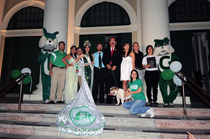 Los actos protocolarios que marcaron el inicio de la actividad se llevaron a cabo en las escalinatas de la Casa Alcaldía de Mayagüez. En la foto, funcionarios del RUM y del Municipio rodeados por las mascotas del Colegio y acompañados por las Reinas que representan al Recinto.