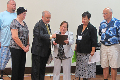 La doctora Darnyd Ortiz (en el centro) lee la dedicatoria al fenecido profesor Julio C. Ríos, la acompañan familiares del profesor, representantes de INCI y SaGES. Observa Mary Ellen Campbell (segunda desde la derecha), viuda de Ríos.