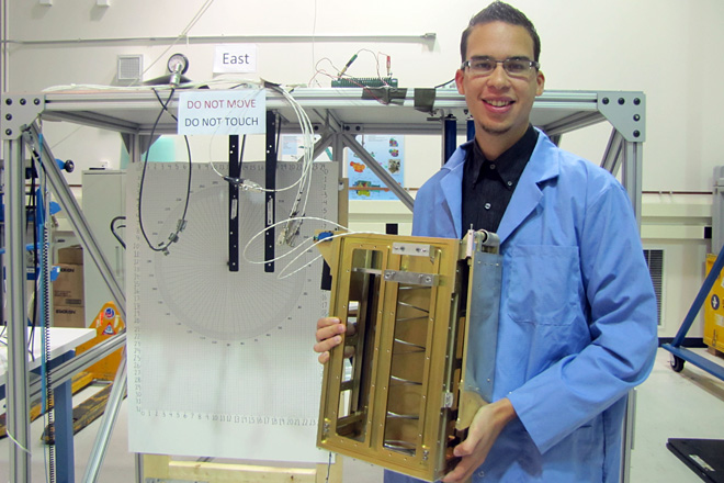 Christopher Ayala Feliciano, frente al <em>test stand</em> sosteniendo el <em>SmallSat deployer</em>.<br>Suministrada