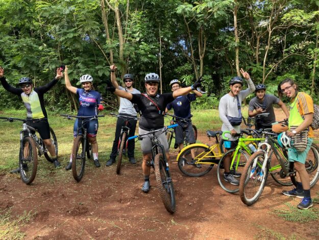 Participantes del recorrido en bicicleta en Monte Pirata con sus bicicletas saludando y levantando las manos.