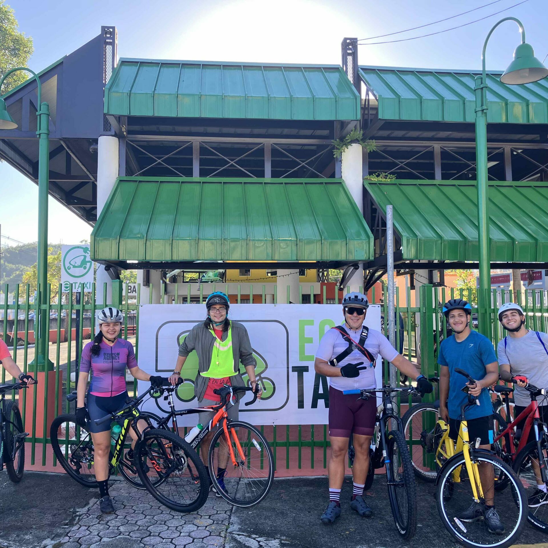 Ciclistas posando frente a las facilidades de Eco Taxi en Mayagüez.