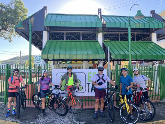 Ciclistas posando frente a las facilidades de Eco Taxi en Mayagüez.