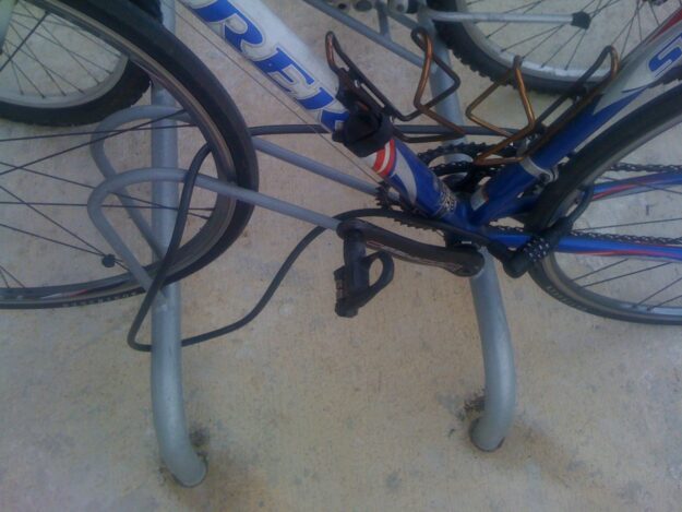 Bicicleta asegurada con un cable de combinación a una percha fija en el suelo.