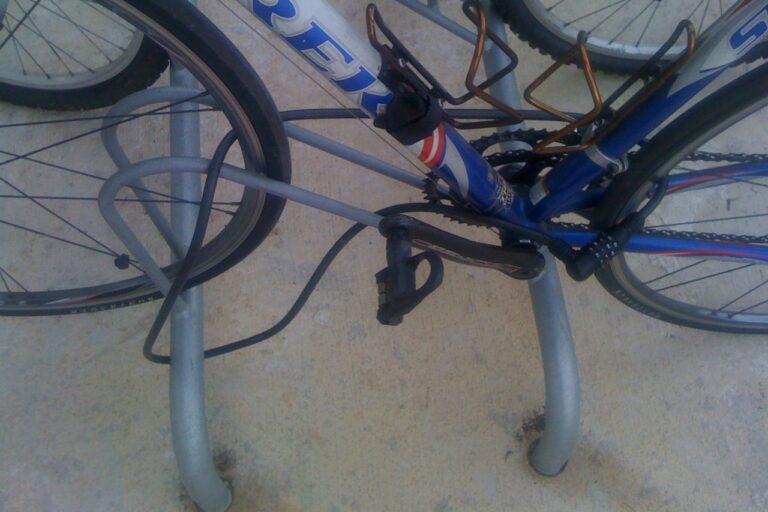 Bicicleta asegurada con un cable de combinación a una percha fija en el suelo.