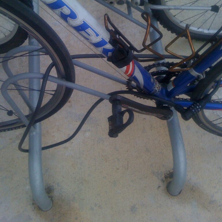 Bicicleta asegurada con un cable de combinación a una percha fija en el suelo.