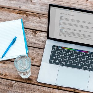 Stock Image of a Laptop computer, a notepad, pen and glass of water. 