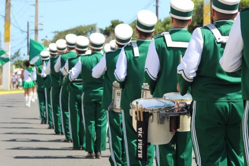 Imagen mostrando estudiantes integrantes de la Banda de Marcha marchando de espalda en una calle