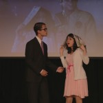 Cast members for the student presented play of The Rocky Horror Picture show on stage. The film is presented in the background.