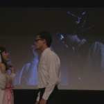 Cast members for the student presented play of The Rocky Horror Picture show on stage with the film being displayed in the background.