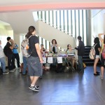 A panoramic shot of the table for the EDSA Book & Bake Sale event. There are customers and team members interacting.