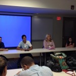 Members sitting at a table listening to the discussion.