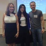 A professor (to the far left) and two students (middle and far right) are posing for the camera.