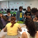 Students gathered around a table partaking in a game, trying to figure out where the books were hidden.