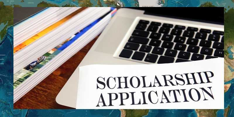 The words Scholarship Application are presented on top of a laptop next to some books.