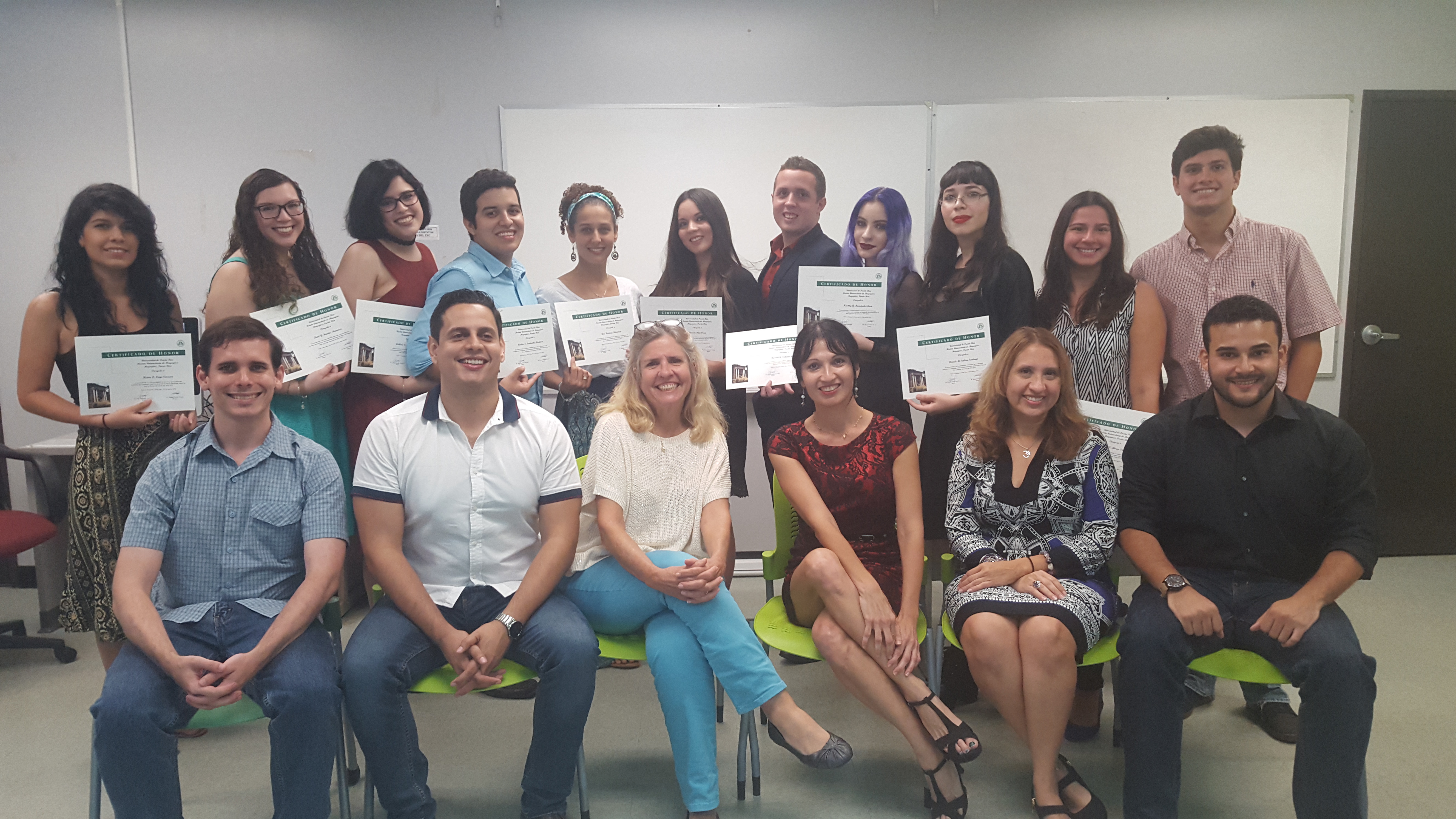 The Honor Roll Students posing for the camera while holding up their certificates (background) and the faculty members posing along with them (foreground).