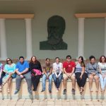 Students sitting in front of a Eugenio Maria de Hostos effigy, posing for the camera.