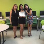 A student is posing for the camera, holding up a certificate, standing in the middle, accompanied by Nancy Vicente (left) and Rosita Rivera (right).