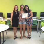 A student is posing for the camera, holding up a certificate, standing in the middle, accompanied by Nancy Vicente (left) and Rosita Rivera (right).