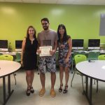 A student is posing for the camera, holding up a certificate, standing in the middle, accompanied by Nancy Vicente (left) and Rosita Rivera (right).