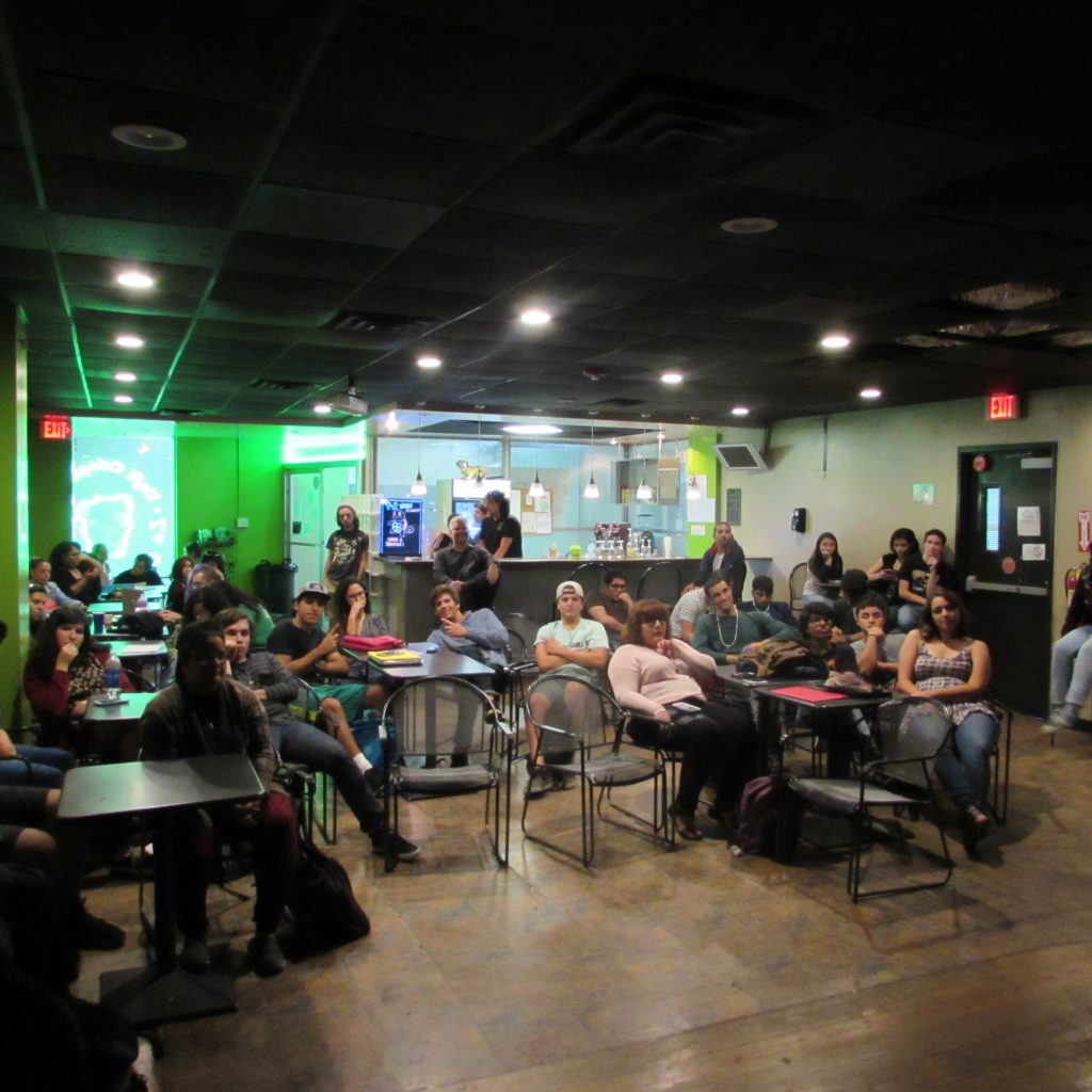 A picture of the audience looking at the stage where someone is presenting.