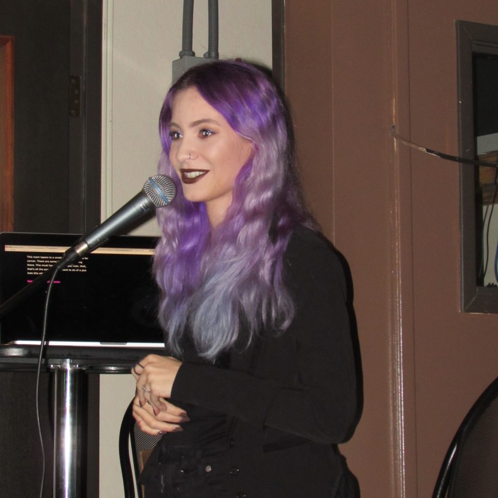 One of the speakers at the event is standing on stage and speaking through a microphone.