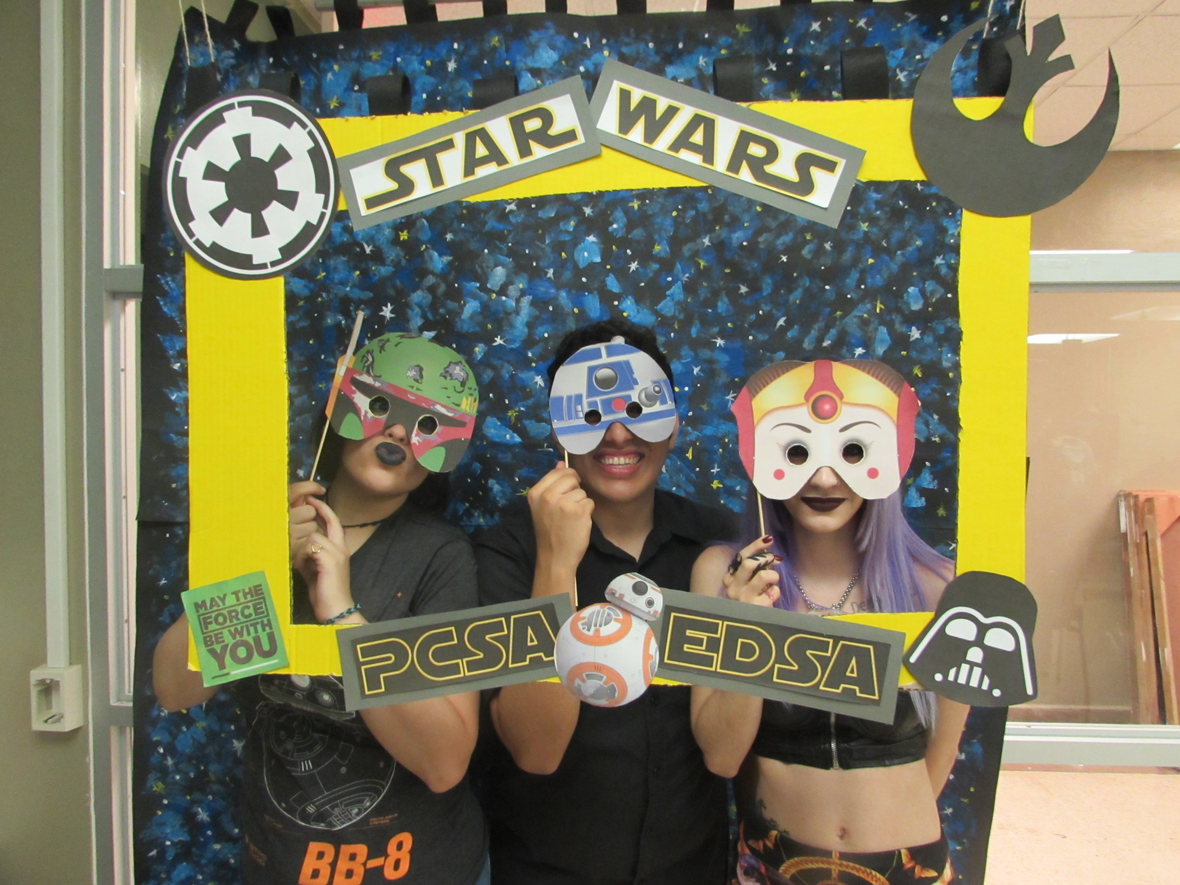 Attendants of the joint activity of May the 4th Be with you by EDSA & PCSA posing for the camera while holding up a promotional frame for PCSA and EDSA and wearing masks.