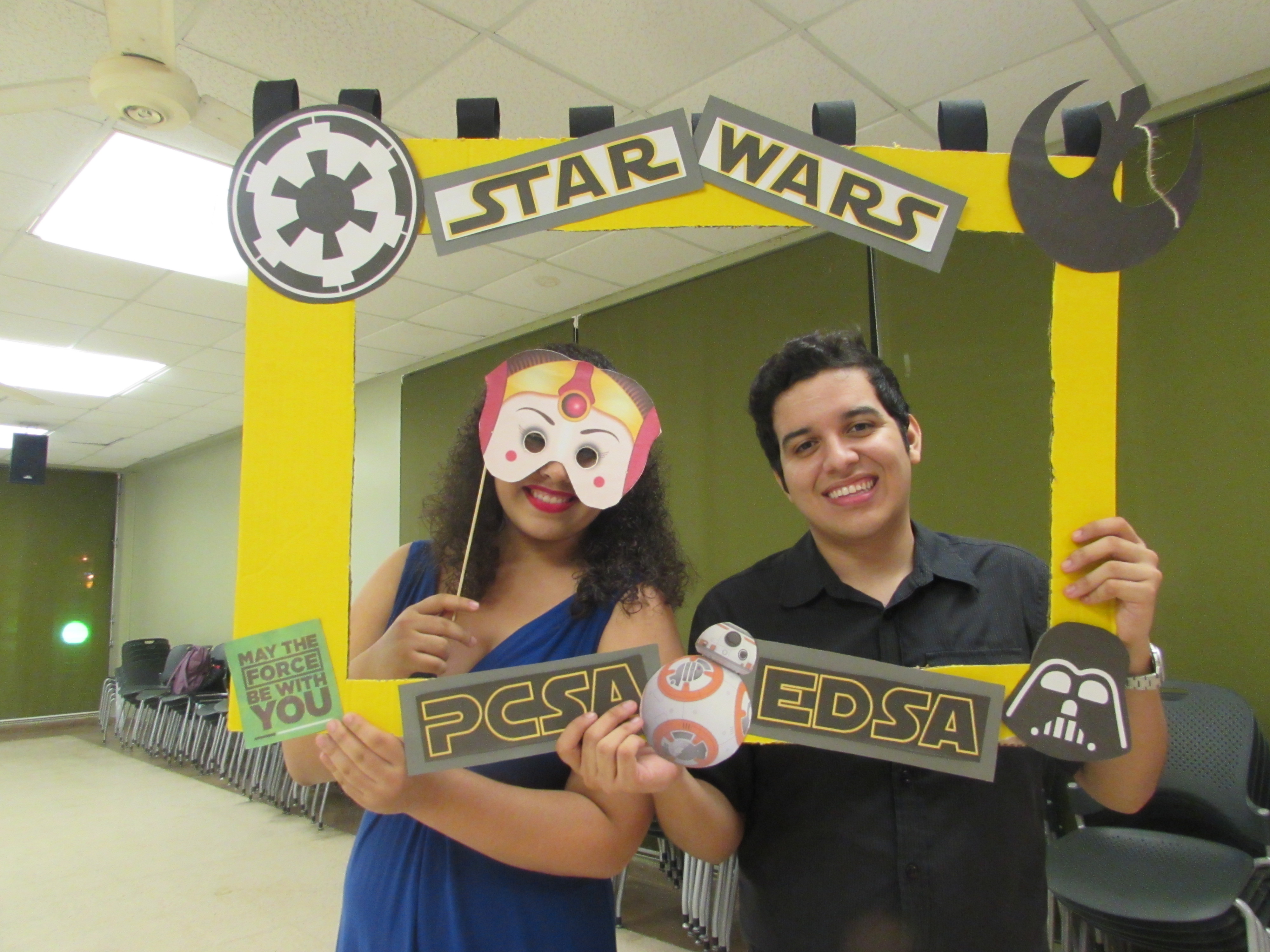 Attendants of the joint activity of May the 4th Be with you by EDSA & PCSA posing for the camera while holding up a promotional frame for PCSA and EDSA and wearing masks.