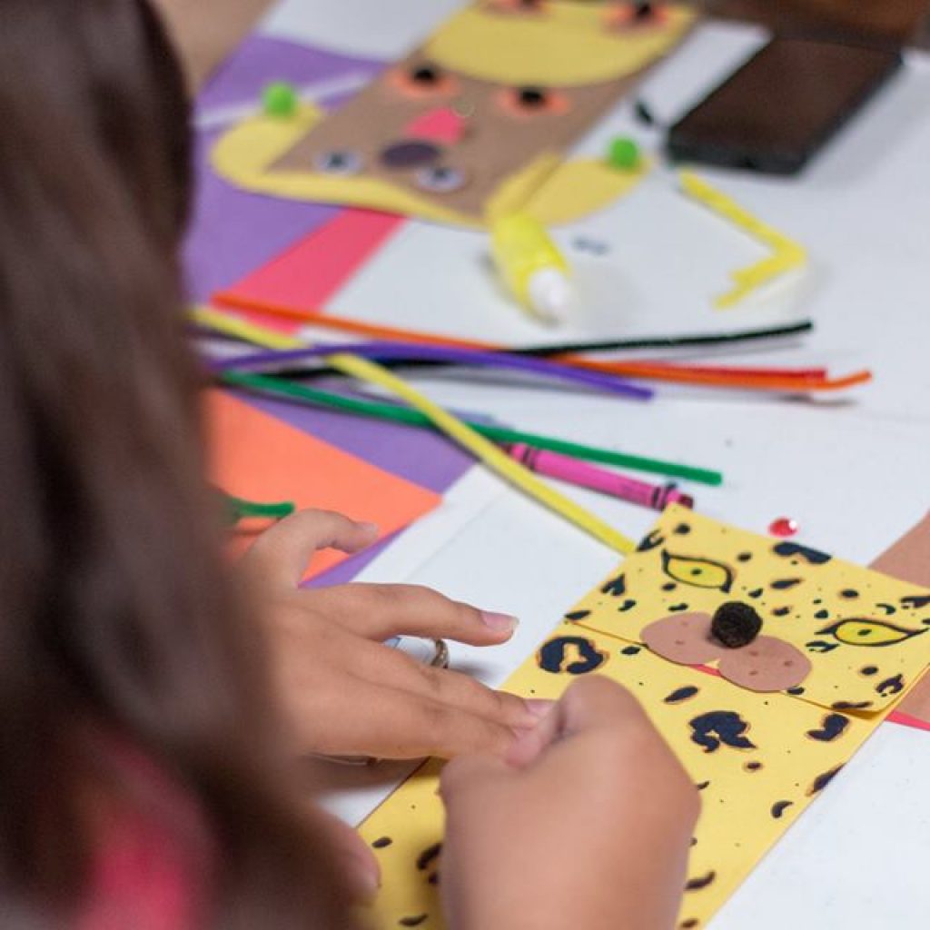 A hand puppet is resting on the table with crayons and other materials for crafts.