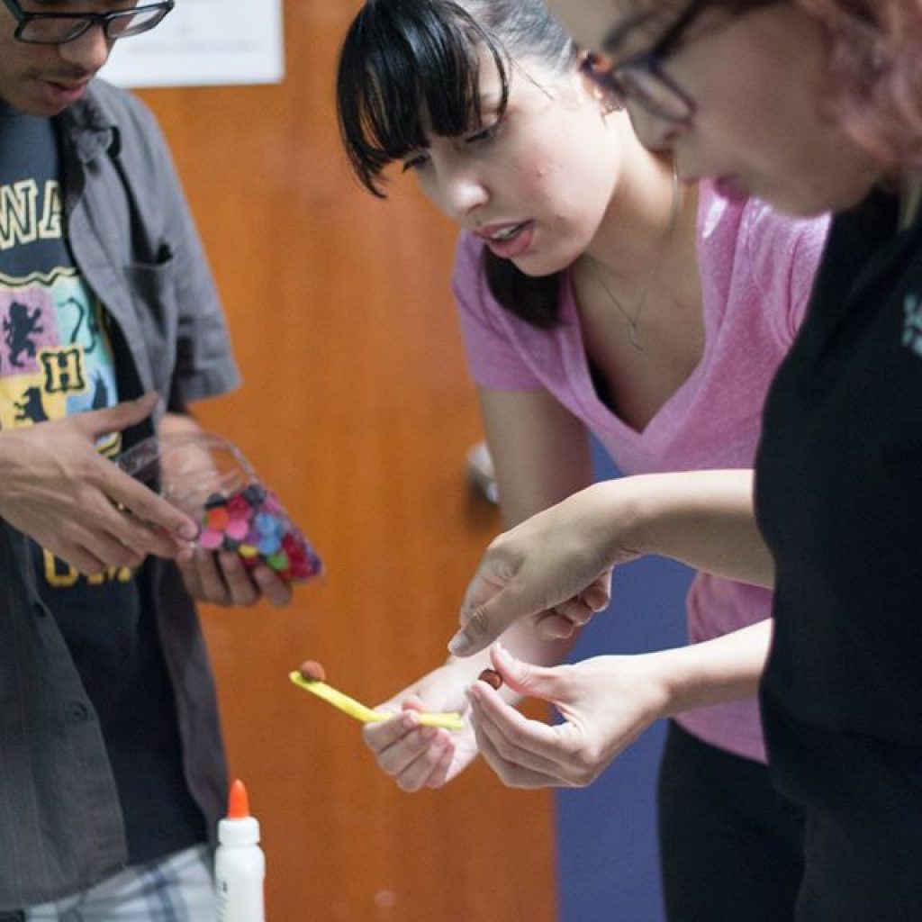 EDSA members helping kids glue some materials together.