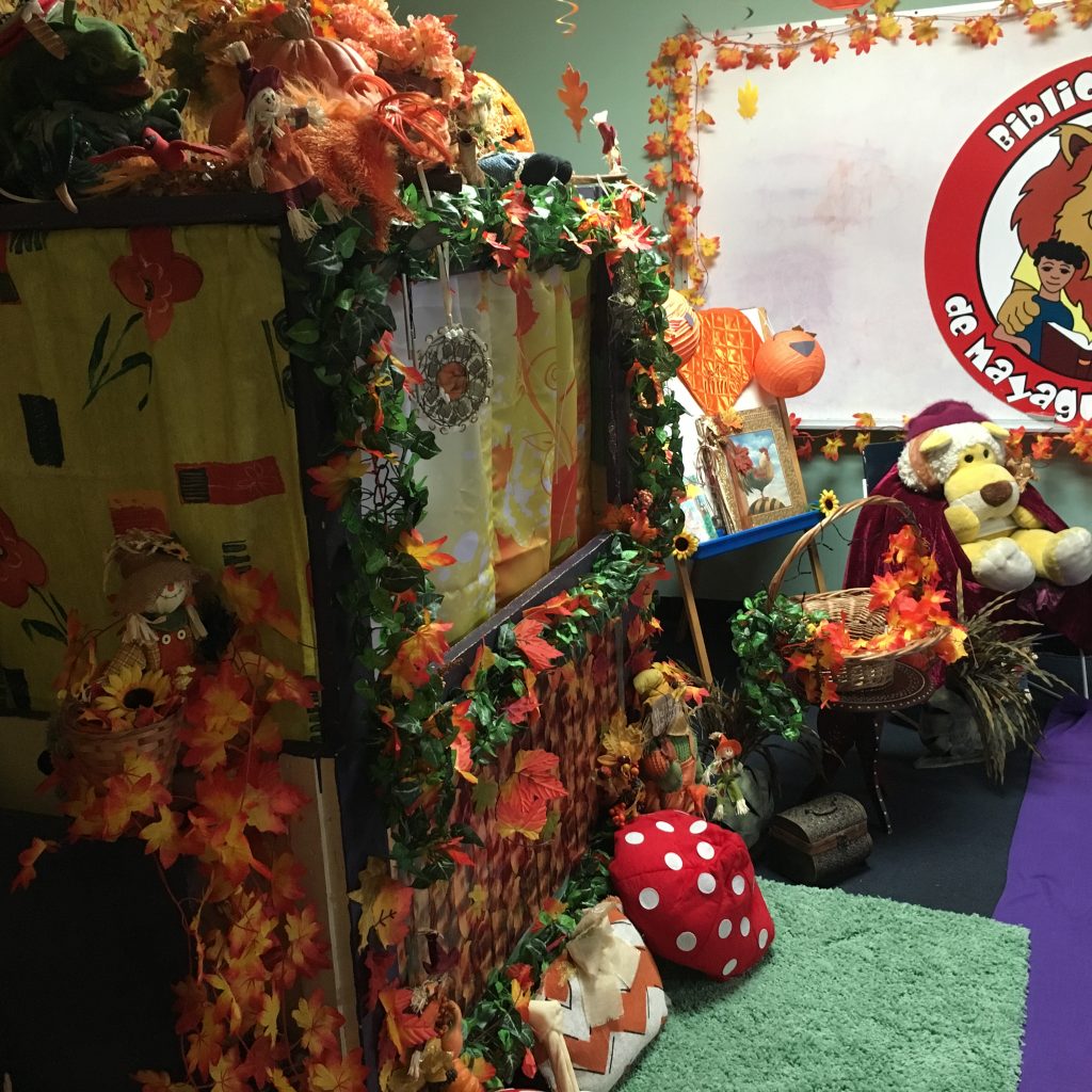 Decorations at the Children's Library Puppet Show. The puppet stage is on the left with several Halloween Themed decorations such as fall colored leaves and carved pumpkins.