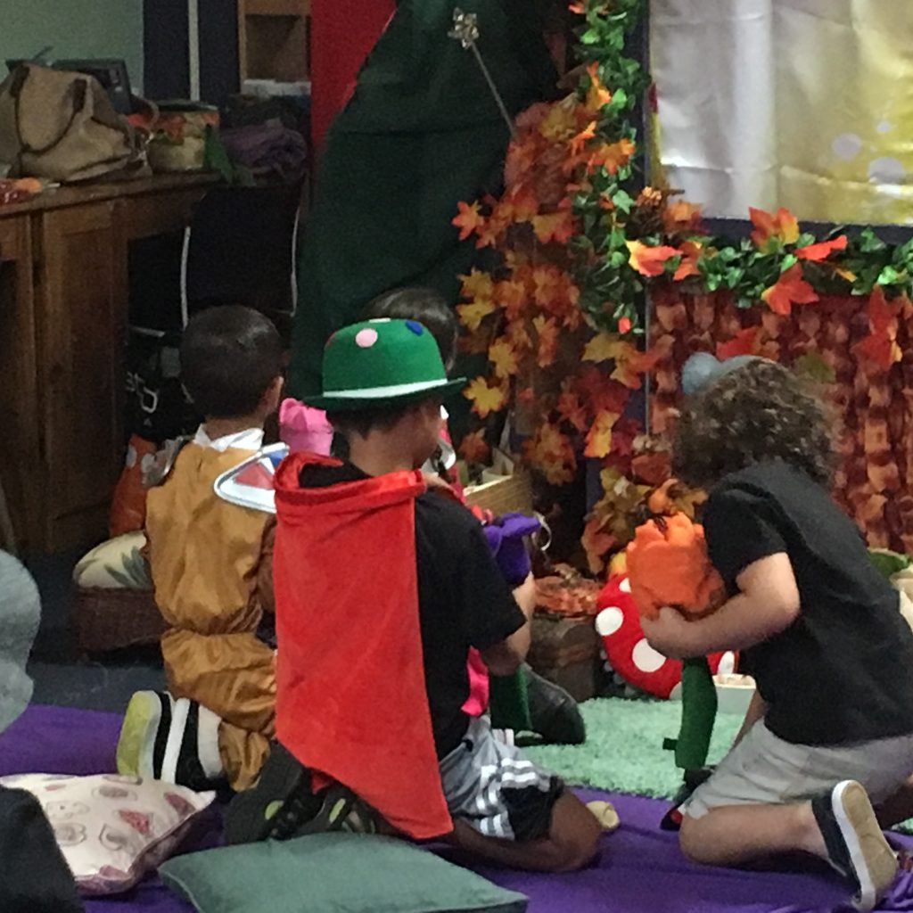 Children are playing close to the puppet stage with different plush towns and other toys found on the floor.