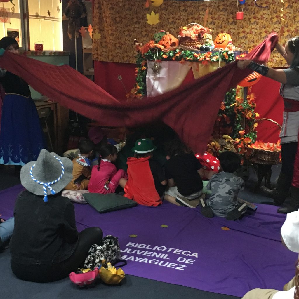 Children are being playfully covered with a blanket at the Children's Library Puppet Show.