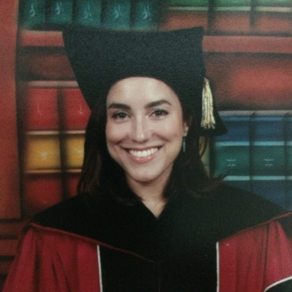 María Quintero Aguiló in her graduation robe smiling for the camera.