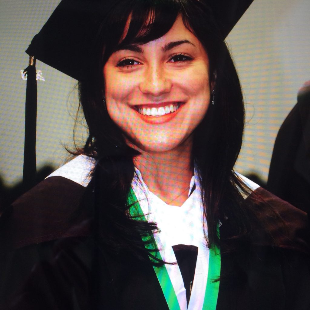 María Quintero Aguiló in her graduation robe smiling for the camera.