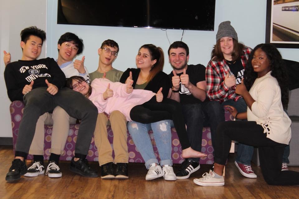 A group of NYU students sitting on a couch, with UPRM student Claudia Rodriguez laying on their laps