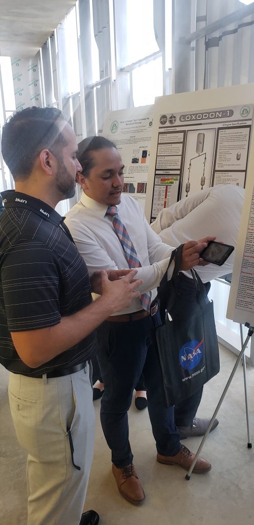 El estudiante Miguel Torres le muestra su investigación al ingeniero Kelkin Ruiz, egresado del RUM que labora en NASA. Foto Mariam Ludim Rosa/Prensa RUM