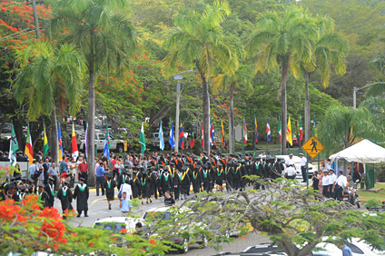 El desfile es una tradición del Recinto. Al fondo, se observan las banderas de los pueblos de Puerto Rico y de los países que representan a los graduados.