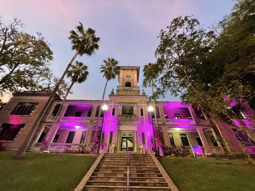 Edificio José de Diego del Recinto Universitario de Mayagüez iluminado con luces rosadas en solidaridad de Octubre Mes de la Prevención de cáncer de seno.
