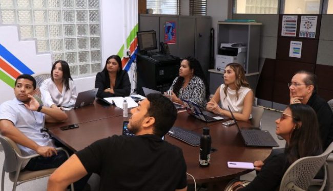 El proyecto: Iniciativa para el fortalecimiento de Organizaciones sin Fines de Lucro para el Desarrollo Económico (NPO-SIED), adscrito al Centro de Negocios y Desarrollo Económico (CNDE), del Colegio de Administración de Empresas (ADEM), del Recinto Universitario de Mayagüez, abrió la convocatoria para su tercera cohorte de organizaciones sin fines de lucro, que deseen recibir mentoría y asistencia técnica por un periodo de seis meses a un año.  Suministrada Grupo de personas toman un adiestramiento en línea y miran la pantalla.