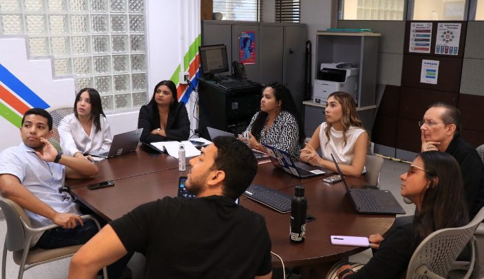 Grupo de personas toman un adiestramiento en línea y miran la pantalla.