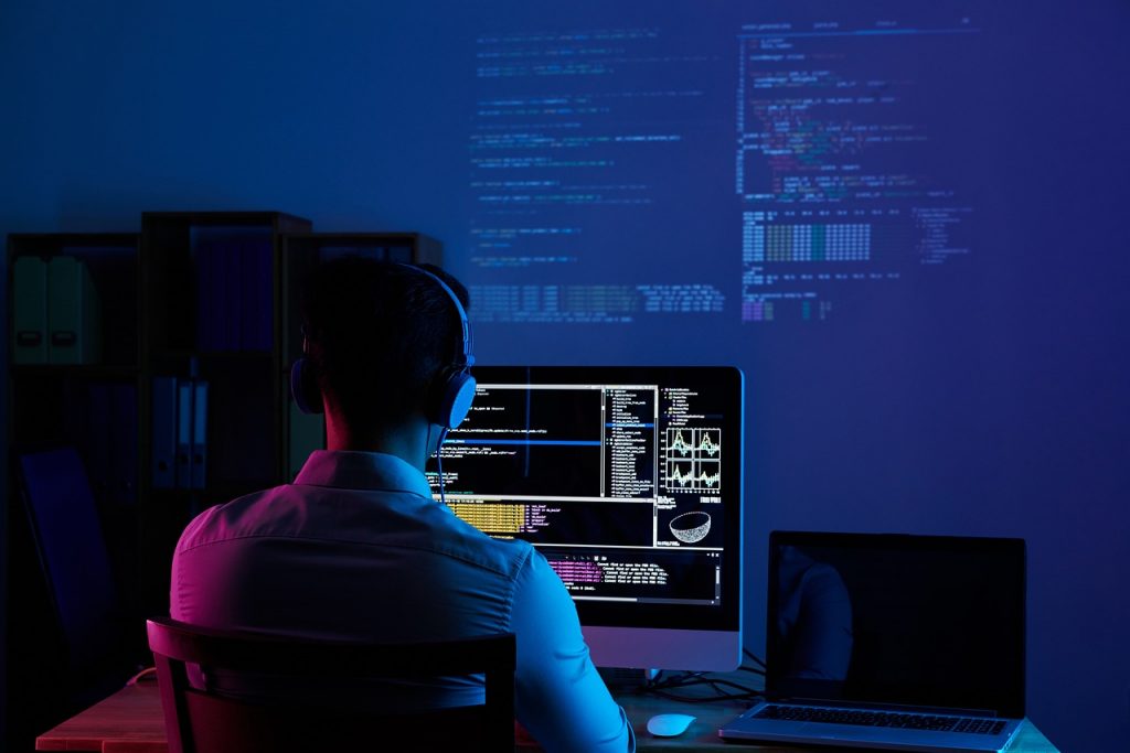 Foto de persona de espalda programando en una computadora.